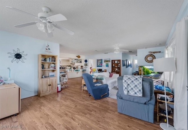 living room featuring ceiling fan, a textured ceiling, and light hardwood / wood-style flooring