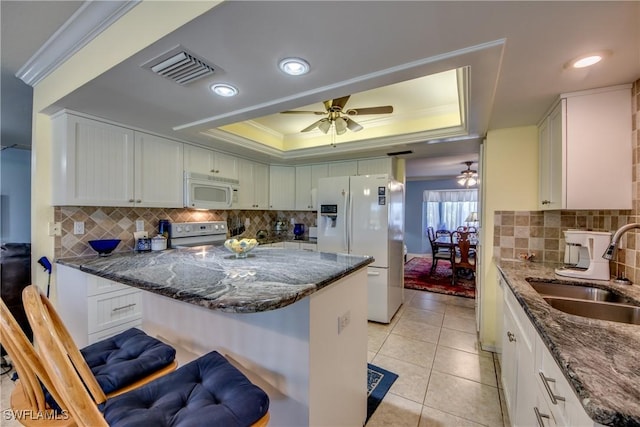 kitchen featuring a breakfast bar, white cabinetry, sink, and white appliances