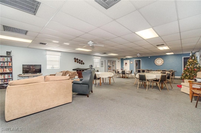 living room with ceiling fan, a drop ceiling, and carpet