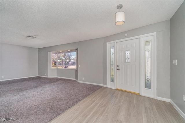 foyer entrance with a textured ceiling and light wood-type flooring