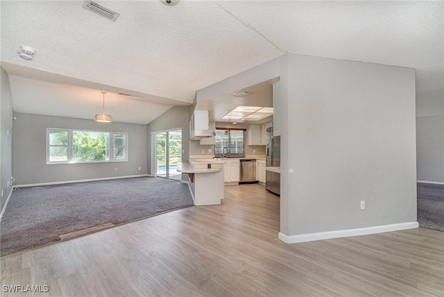 kitchen featuring white cabinets, dishwasher, light wood-type flooring, and decorative light fixtures