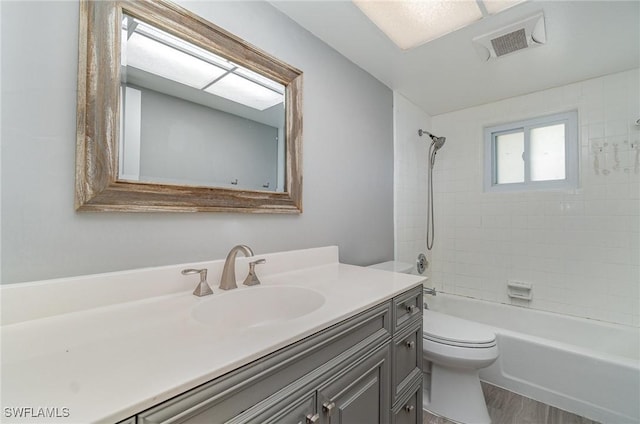 full bathroom featuring hardwood / wood-style flooring, vanity, toilet, and tiled shower / bath