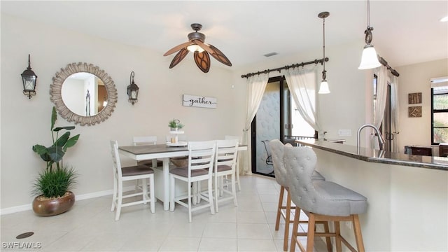 tiled dining space with ceiling fan and sink