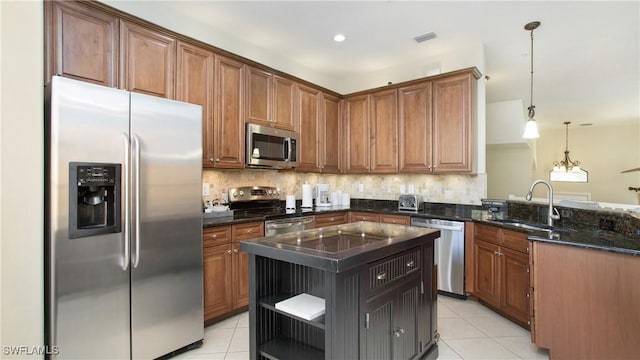 kitchen featuring sink, a center island, tasteful backsplash, decorative light fixtures, and appliances with stainless steel finishes