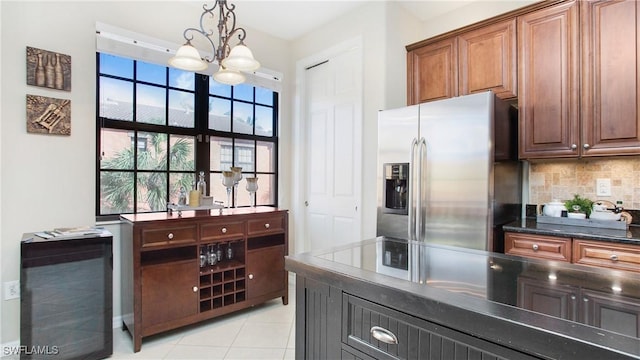 kitchen with an inviting chandelier, light tile patterned floors, tasteful backsplash, decorative light fixtures, and stainless steel fridge with ice dispenser