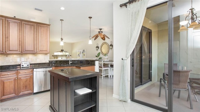 kitchen with a kitchen island with sink, sink, light tile patterned floors, dishwasher, and hanging light fixtures