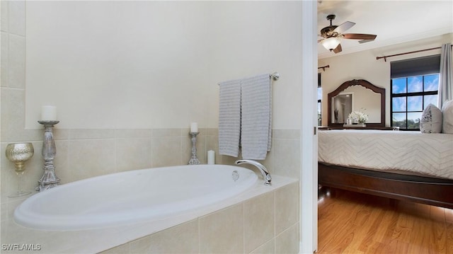 bathroom with hardwood / wood-style floors, ceiling fan, ornamental molding, and tiled bath