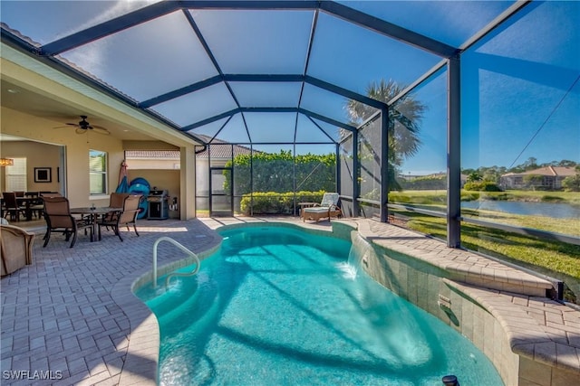 view of swimming pool with glass enclosure, ceiling fan, pool water feature, a water view, and a patio