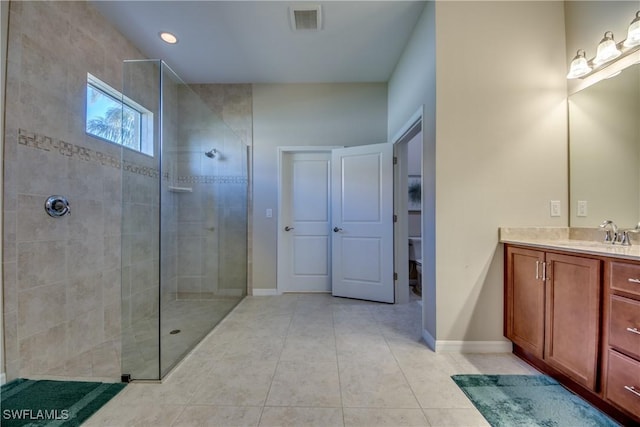 bathroom featuring tiled shower, vanity, and tile patterned flooring