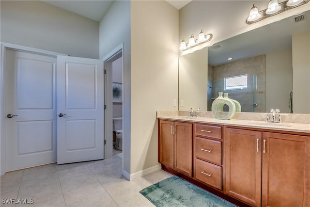 bathroom with tile patterned floors, toilet, vanity, and tiled shower