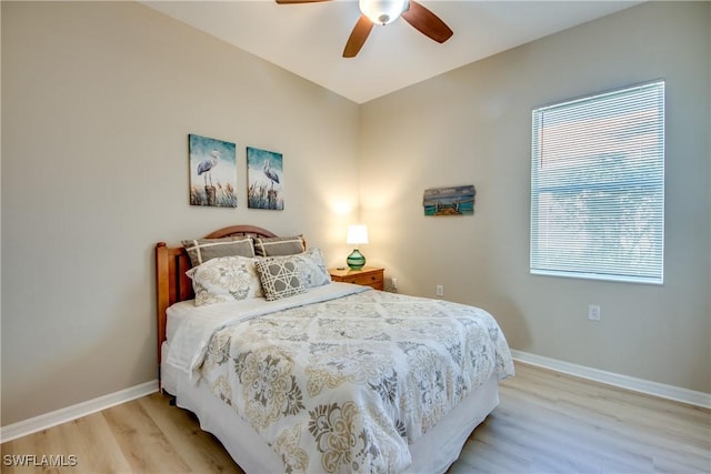 bedroom featuring ceiling fan, light wood-type flooring, and multiple windows