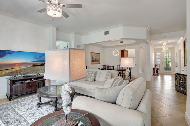 living room with ceiling fan with notable chandelier, light tile patterned flooring, and crown molding