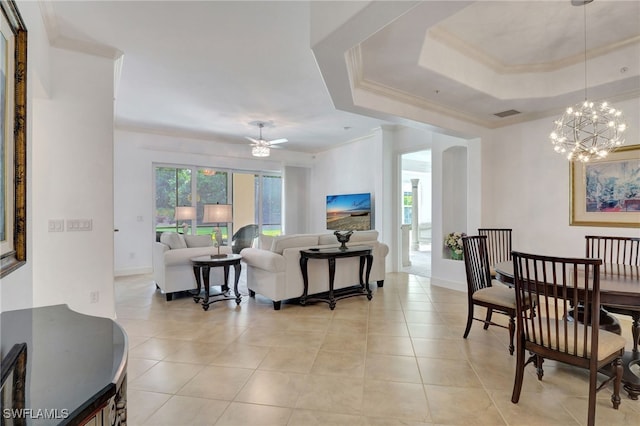 tiled living room featuring a raised ceiling, crown molding, and ceiling fan with notable chandelier