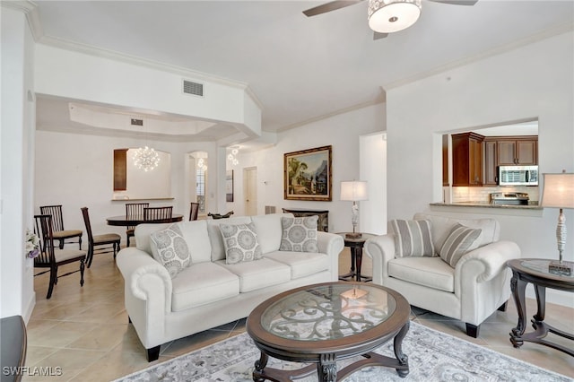 living room with light tile patterned floors, ceiling fan with notable chandelier, and ornamental molding