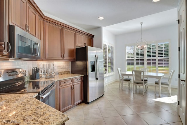 kitchen with backsplash, light stone countertops, stainless steel appliances, and decorative light fixtures