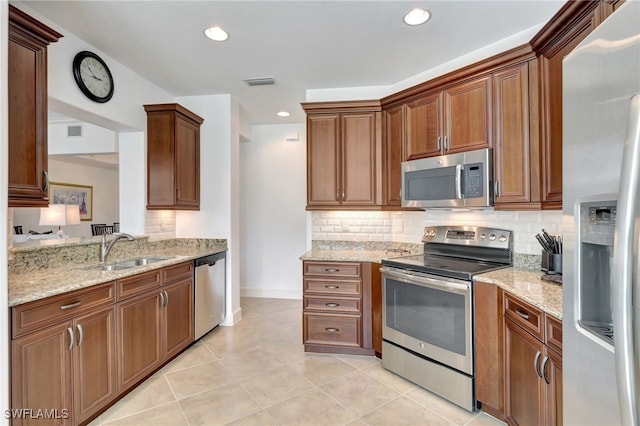 kitchen featuring backsplash, sink, light tile patterned floors, light stone counters, and stainless steel appliances