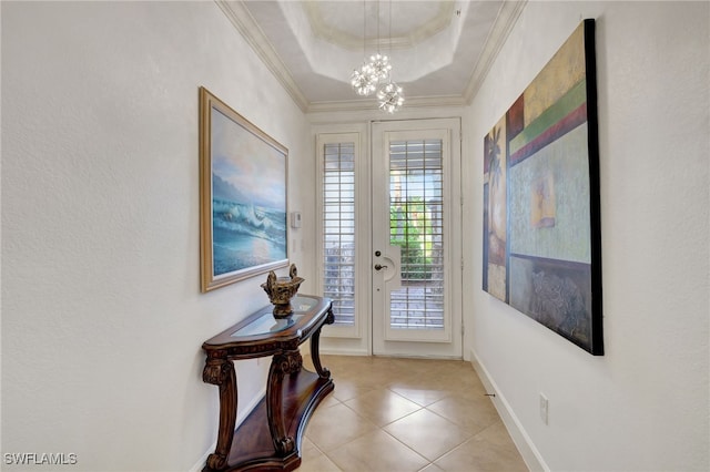 entryway featuring a raised ceiling, crown molding, light tile patterned flooring, and a chandelier