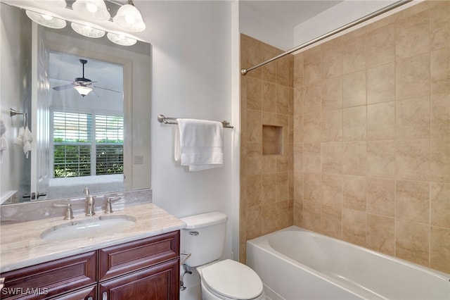 full bathroom with vanity, tiled shower / bath combo, toilet, and ceiling fan