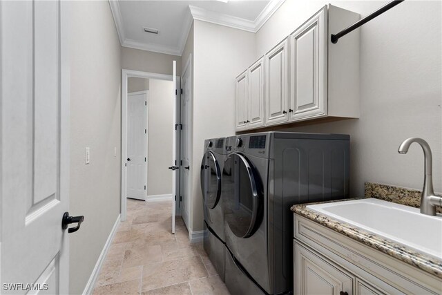 clothes washing area featuring cabinets, washer and clothes dryer, ornamental molding, and sink