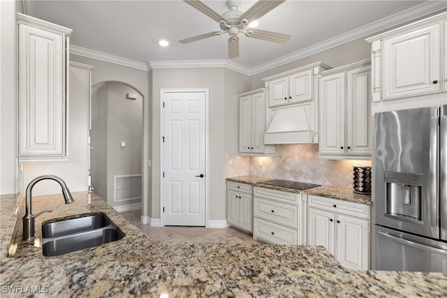 kitchen with stainless steel refrigerator with ice dispenser, black electric cooktop, white cabinetry, and custom range hood