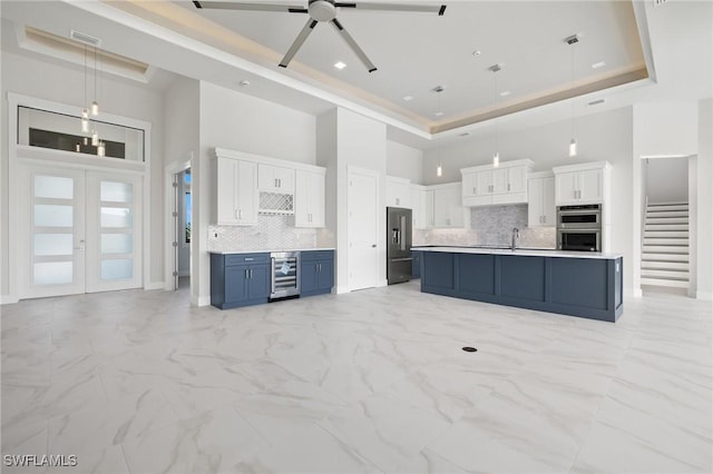 kitchen with white cabinetry, blue cabinets, hanging light fixtures, and a high ceiling