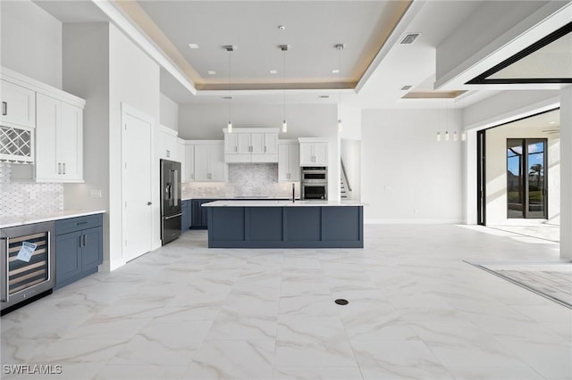 kitchen with appliances with stainless steel finishes, backsplash, white cabinetry, and blue cabinets