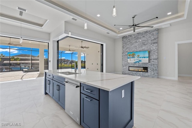 kitchen featuring decorative light fixtures, a stone fireplace, a raised ceiling, and sink