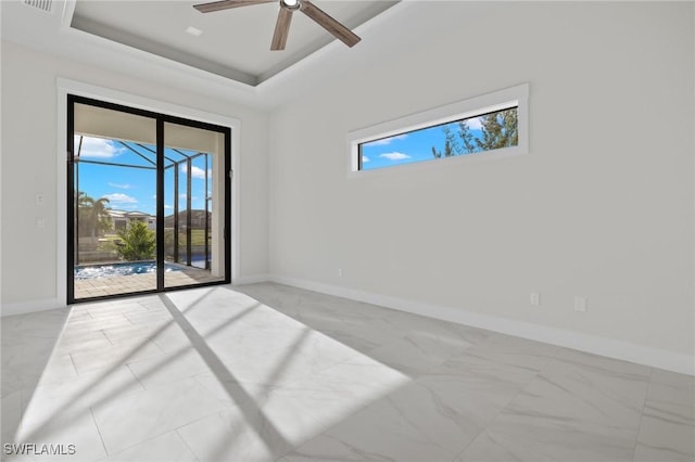 spare room with ceiling fan and a raised ceiling