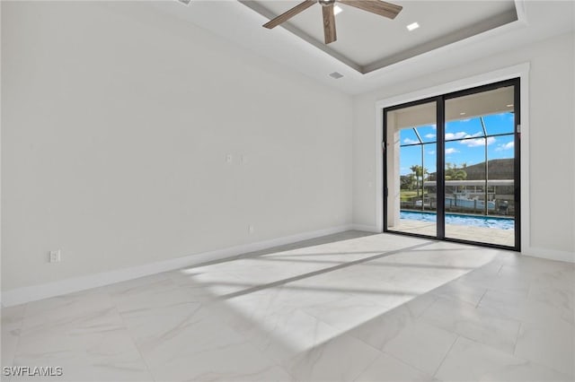 empty room featuring a tray ceiling and ceiling fan