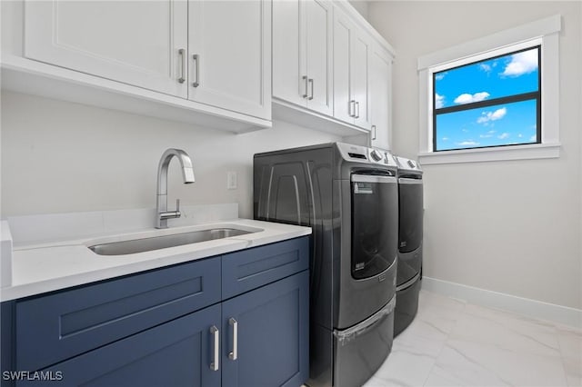 washroom with cabinets, washing machine and dryer, and sink