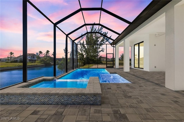 pool at dusk featuring an in ground hot tub, a patio area, and a lanai