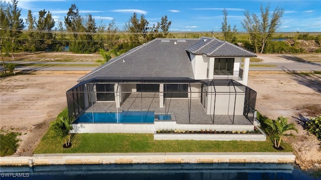 rear view of property featuring a patio, a water view, and glass enclosure