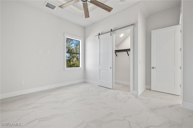 unfurnished bedroom with a barn door, a closet, and ceiling fan