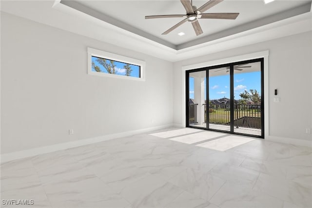 unfurnished room featuring a raised ceiling, ceiling fan, and a healthy amount of sunlight