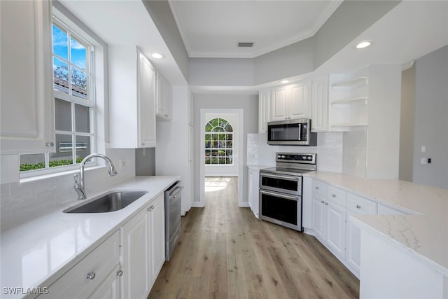 kitchen featuring appliances with stainless steel finishes, white cabinetry, plenty of natural light, and sink