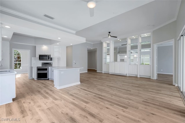 unfurnished living room featuring ceiling fan, light wood-type flooring, sink, and ornamental molding