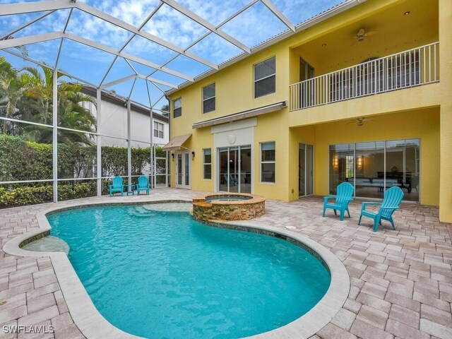 rear view of property with glass enclosure, a pool with hot tub, ceiling fan, a balcony, and a patio area