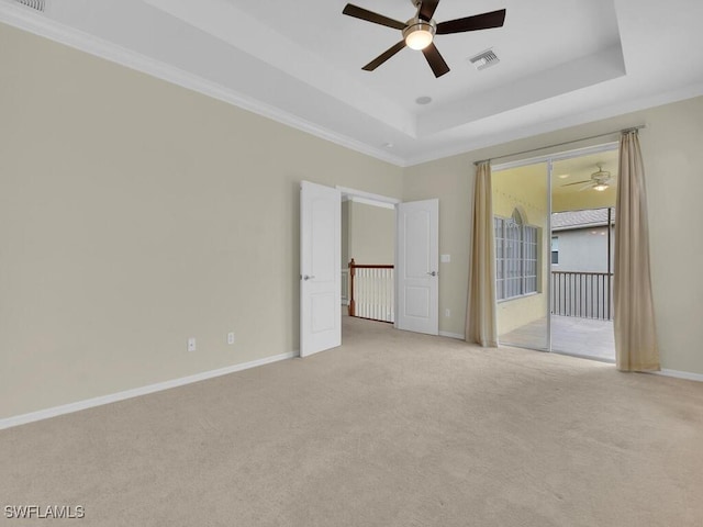 unfurnished bedroom featuring a raised ceiling, ceiling fan, light colored carpet, and ornamental molding