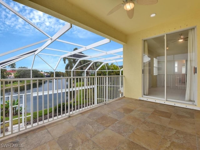 view of patio with glass enclosure, ceiling fan, and a water view