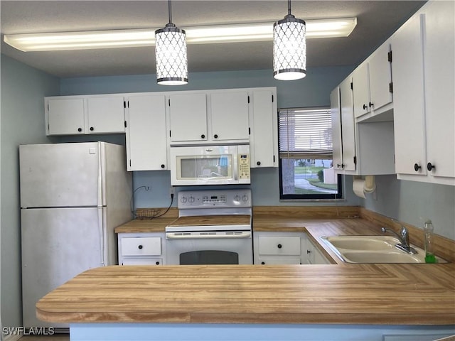 kitchen with kitchen peninsula, white appliances, sink, white cabinets, and hanging light fixtures