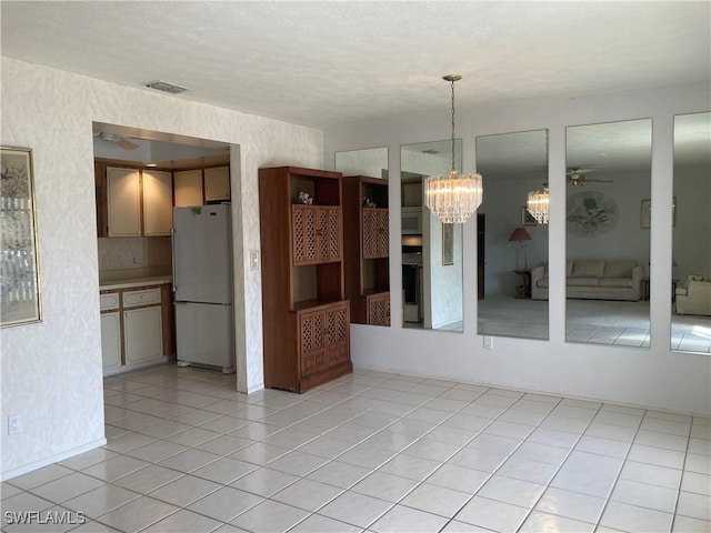 unfurnished dining area with light tile patterned floors and ceiling fan with notable chandelier