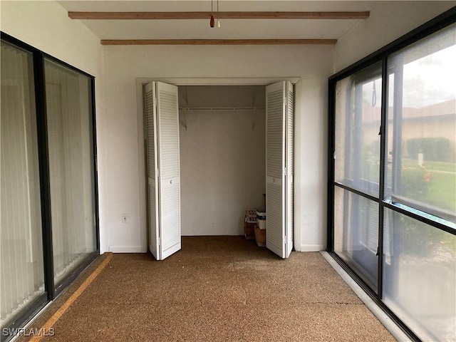 unfurnished bedroom featuring beam ceiling and carpet floors