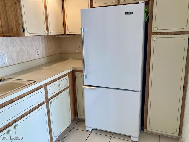 kitchen featuring white fridge, light tile patterned floors, and sink