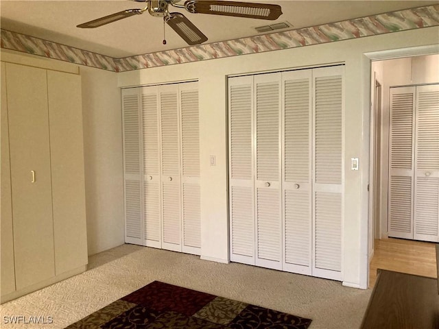 unfurnished bedroom with carpet, ceiling fan, and multiple closets