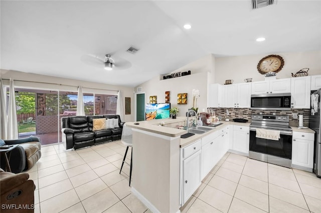 kitchen featuring white cabinets, sink, vaulted ceiling, appliances with stainless steel finishes, and kitchen peninsula