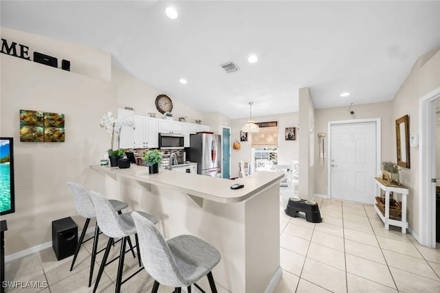 kitchen featuring kitchen peninsula, appliances with stainless steel finishes, a kitchen breakfast bar, pendant lighting, and white cabinetry