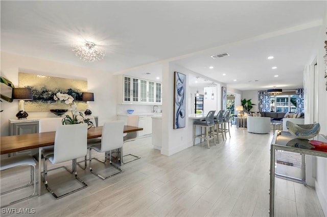 dining area with light wood-type flooring and an inviting chandelier