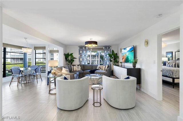 living room with light hardwood / wood-style flooring, a healthy amount of sunlight, and a notable chandelier