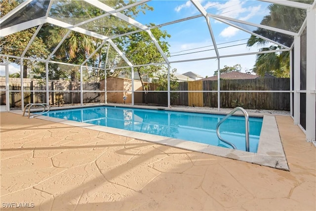 view of pool with a lanai, a patio area, and a storage shed