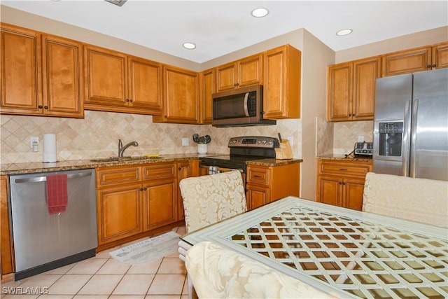 kitchen with light stone countertops, sink, backsplash, light tile patterned flooring, and appliances with stainless steel finishes